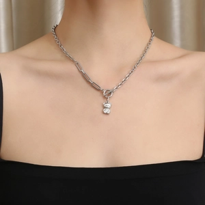 Close-up of bear pendant on mixed paperclip chain necklace worn by a model