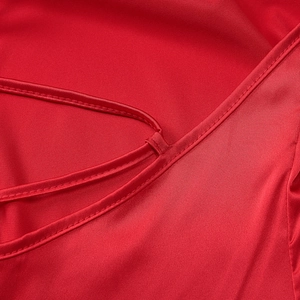 Close-up of thin shoulder strap and stitching on red satin bodycon summer dress