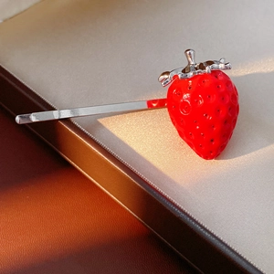 Dettaglio macro di un fermaglio per capelli a fragola rossa con strass scintillanti