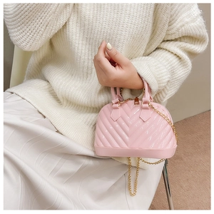 Detail of pink jelly shell bag with V-quilted texture and gold chain strap on a model