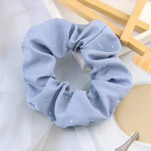 Light blue fabric scrunchie with silver polka dots on a soft white background