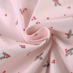 Gros plan détaillé du tissu en maille rose clair avec motif floral de baies et feuilles