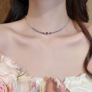 Close-up of purple zircon amethyst beaded necklace worn by a model in soft light