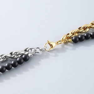 Detailed view of bicolor gold and silver chains with black matte beads and lobster clasp
