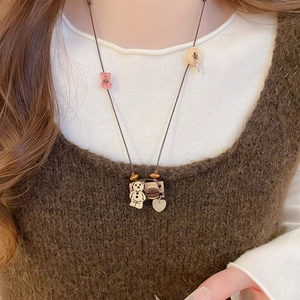 Detailed close-up of a forest-style necklace with teddy bear, coffee bean, and heart charms