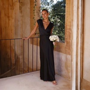 Elegant detail of black satin V-neck maxi dress showing smooth texture on sunlit terrace