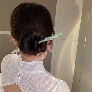 Détail d'un pic à cheveux style chinois moderne avec feuilles bleues sur chignon élégant