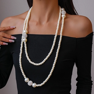 Close-up of double-layer long pearl necklace with silver crystal-studded spheres on neck