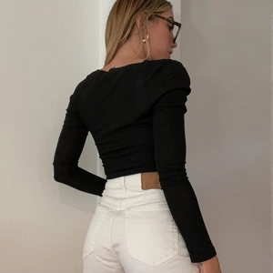 Dettaglio del design stringato sul retro di un top nero a maniche lunghe dalla vestibilità slim