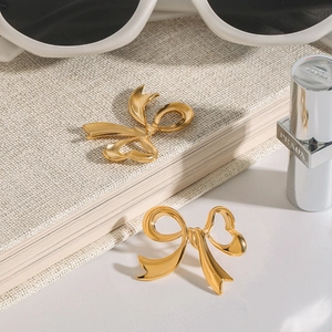 Polished gold bow earrings made of titanium steel displayed on a minimalist surface