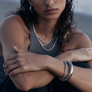 Close-up of minimalist silver stainless steel necklace and cuff bracelet on a model