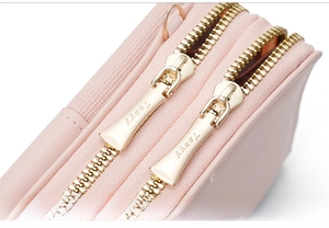 Detail of pink leather phone bag featuring high-quality double gold zippers and metal logo