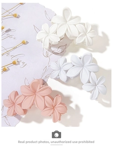 Detailed macro view of three matte flower hair claws in white, blue, and pink colors
