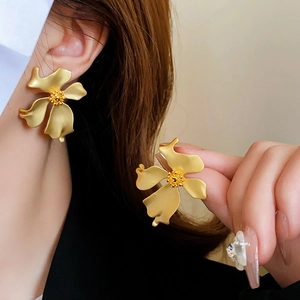 Detailed close-up of matte gold flower stud earrings with vintage metallic texture