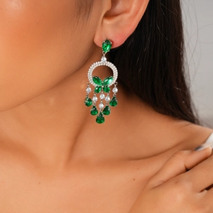 Close-up of green teardrop gemstone tassel earrings with floral zircon accents on model