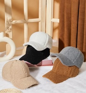 Close-up of thick fleece baseball caps in five colors on a soft white carpet