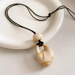 Close-up of teardrop resin pendant with marble texture on black wax cord necklace
