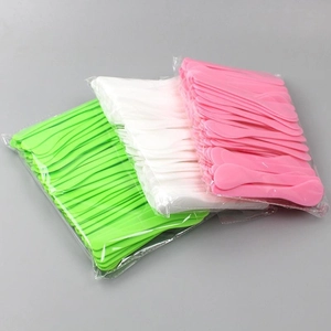 Green, white, and pink plastic facial mask spatulas in transparent packaging bags