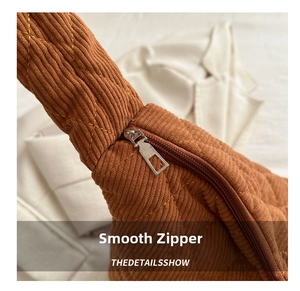 Detail of smooth metal zipper and quilted corduroy texture on large brown tote bag