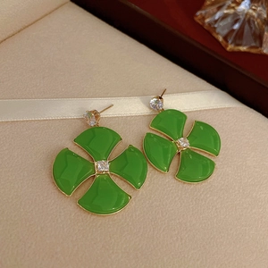 Gros plan de boucles d'oreilles trèfle dorées avec émail vert et zircons brillants
