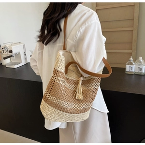 Detail of woven straw shoulder bag with leather strap and tassel decoration in a cafe setting