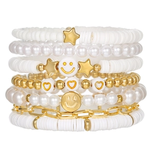Detail view of layered boho white and gold bracelets with smiley faces and heart charms