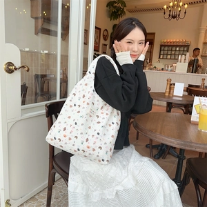 Detailed view of cream quilted tote bag featuring colorful cartoon bear and floral prints