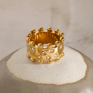 Macro shot of gold wide band ring featuring white cubic zirconia and bead edge details