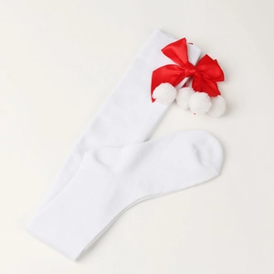 Close-up of white knitted Christmas socks with red satin bows and white plush pom-poms