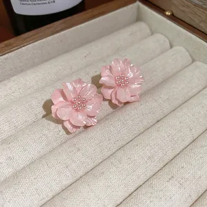 Orecchini a perno con fiori rosa e centri di perle in una scatola per gioielli beige