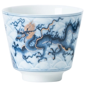 Ceramic Kung Fu teacup with blue and white dragon pattern and gold trim on white background
