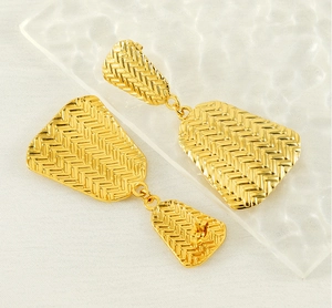 Detailed view of long geometric 18K gold-plated earrings with woven texture and vintage style