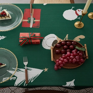 Close-up of green festive tablecloth featuring white Christmas trees and snowmen patterns