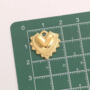 Macro shot of gold heart pendant with radial texture on a metric green cutting mat