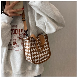 Detail of a brown and white houndstooth tote bag with brown canvas shoulder strap