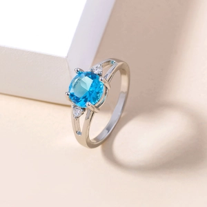 Macro shot of silver ring featuring oval blue gemstone and micro-pave cubic zirconia