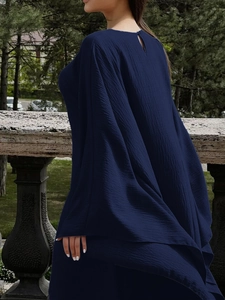 Détail d'une élégante robe plissée bleu foncé à manches longues et dos ajouré raffiné