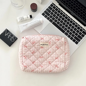 Pink checkered quilted cosmetic bag with bow embroidery and cream brand label on top
