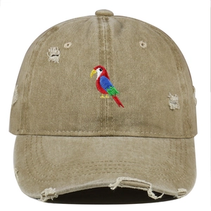 Detailed view of colorful parrot embroidery on khaki distressed washed cotton baseball cap