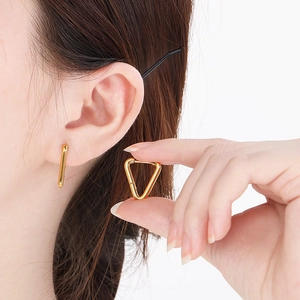 Detailed view of gold stainless steel geometric earrings worn on ear with triangle design