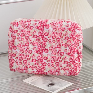 Detailed macro of the quilted floral toiletry bag showing red flower pattern and zipper