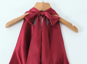 Détail du nœud de cou en satin bordeaux montrant le grand ruban et l'éclat soyeux