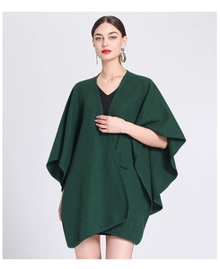 Deep green oversized knit poncho cape for women shown on a model in a professional studio