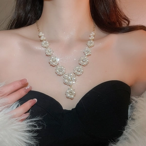 Detail shot of elegant floral faux pearl and rhinestone necklace on a black evening gown