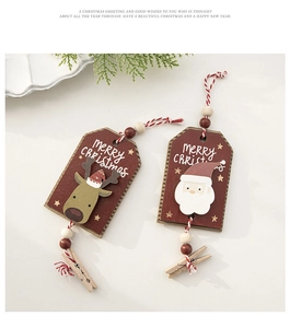 Detail of wooden Christmas clips with reindeer and Santa designs on pine branch