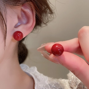 Close-up of red spherical geometric stud earrings with high-gloss mirror finish for women