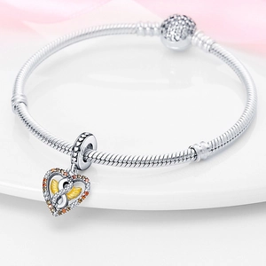 Macro shot of silver snake chain bracelet featuring a heart charm with golden infinity detail