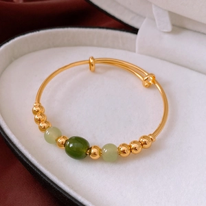Detail of 18k gold plated adjustable bangle with green jade-like beads in luxury jewelry box
