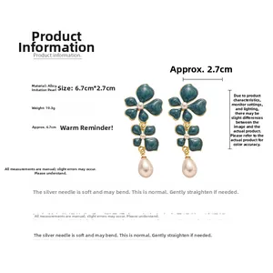 Detailed view of flower earrings with green enamel petals and large teardrop pearls