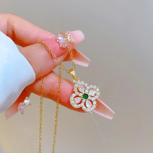 Macro shot of gold clover necklace featuring a green center stone and white crystals